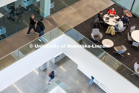 Students roam the hallways while others study at the tables in the commons area inside Kiewit Hall. 