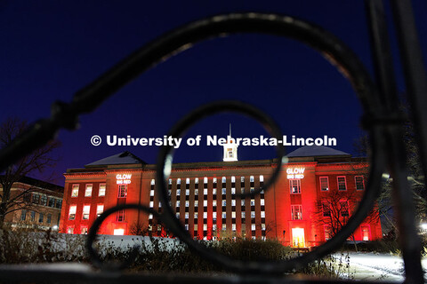 Love Library is lit up in red with gobos projected on the front saying, “Glow Big Red”. Glow Big