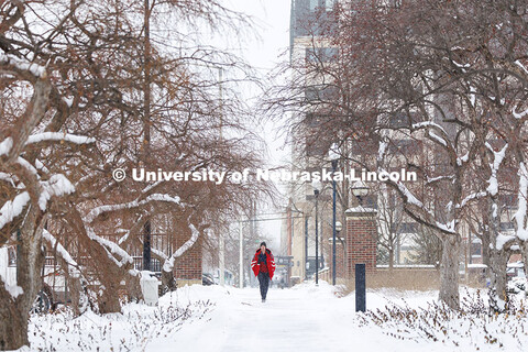 Student crossing the snow-covered campus near the entrance gates on R Street. Snow on City Campus. F