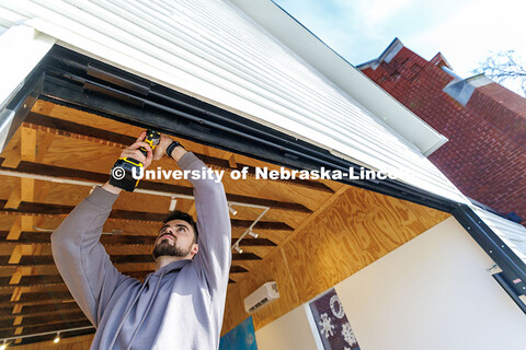Devyn Beekman, third year architecture student, removes a weather strip from the entrance. Art Chape