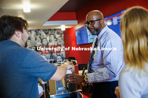 Chancellor Rodney D. Bennett hands a cup of coffee to Cayden Chapman (left), a Business Graduate Stu