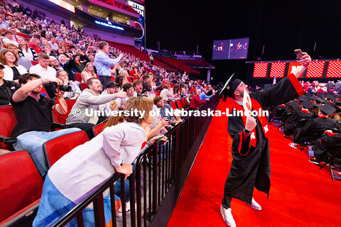 Business Administration graduate Jarrett Michie holds his phone up to get a selfie with more than a 