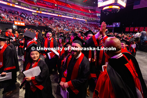 Chancellor Rodney D. Bennett high-fives a student as graduates exit Pinnacle Bank Arena after the Un