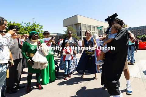 Family members of College of Business graduate Je'Cory Harris hold signs and take photos as he poses