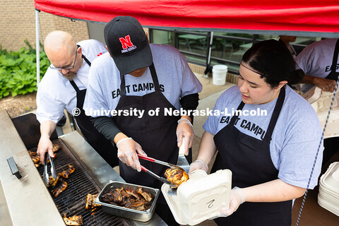 Franklin Yankton uses a spatula and tongs to place a piece of smoked chicken into a to-go box held b