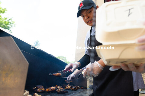 Franklin Yankton holds a piece of chicken steady on a spatula as he moves it from the grill to a to-