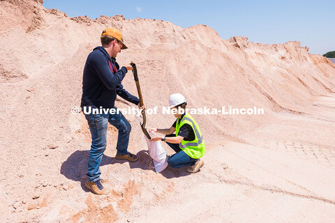 Jake Venne, lab technician for Barkley Asphalt, scoops aggregate gravel into a sample bag for Taisa 