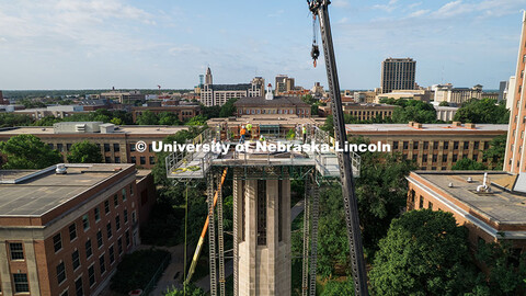 Construction workers stand on scaffolding near the top of Mueller Tower. The tower is undergoing a r