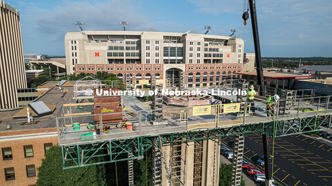 Construction workers stand on scaffolding near the top of Mueller Tower. The tower is undergoing a r