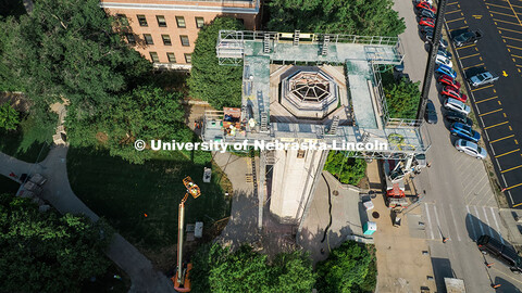 Construction workers stand on scaffolding near the top of Mueller Tower. The tower is undergoing a r