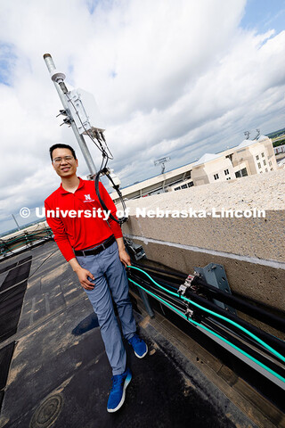 Qiang Liu, assistant professor in the School of Computing, stands next to one of the Husker-Net 5G a