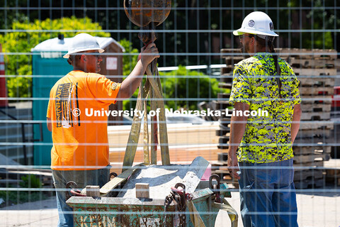 Ostin Gustafson (left) and Charles Tucker unhook a bucket filled with exterior stone removed from Mu