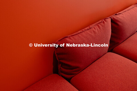 An orange couch is situated against an orange-painted wall in a study nook on the second floor of th