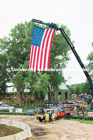 Firefighters watch the Saline County Fair Figure 8 Race in Crete, Nebraska while standing under the 