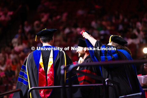 Vinicius Andrade smiles as he is hooded during the summer commencement ceremony. Summer Commencement