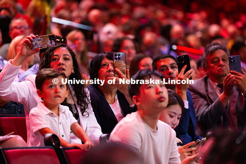 Family members watch as Christian Lopez Ruano walks on stage to be hooded during the summer commence