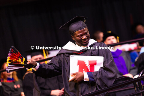 Oluseye Fakinlede snaps open a fan after receiving his master's degree from the College of Journalis