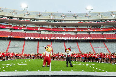 Lil' Red and Herbie Husker stand in front of the freshman as the students form an N on the Memorial 