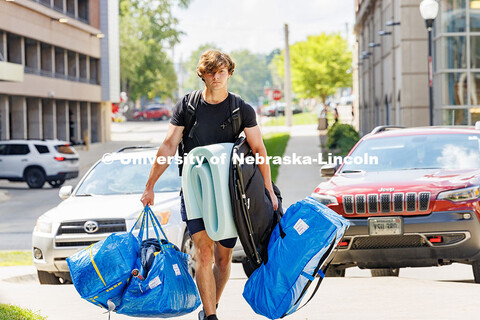 Carsen Davis carries several blue bags into University Suites on move-in day. Residence hall move-in