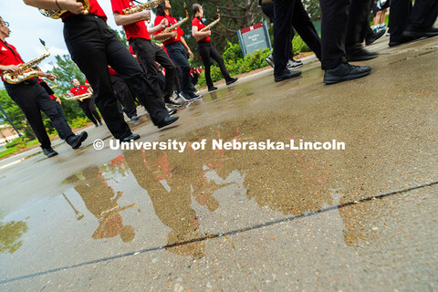 Saxophone players are reflected in a puddle outside of Hamilton Hall as band members march to Memori