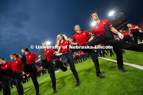 Drum majors, with white stripes on their polos, and members of the pit join together for a can-can l