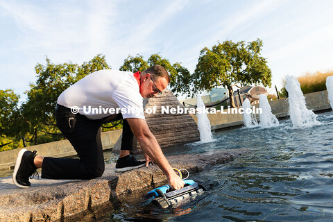 Jon Jenkin, facility manager, places a robotic pool skimmer into Broyhill Fountain. Jenkin manages t