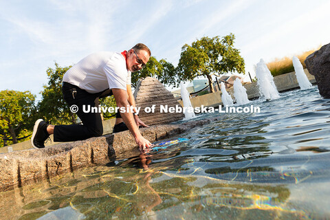 Jon Jenkin, facility manager, glances up while placing a robotic pool skimmer into Broyhill Fountain