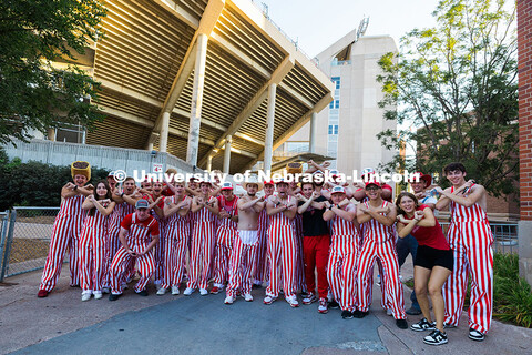 Husker students wear bibs and pose for a group photo outside of Memorial Stadium before the football