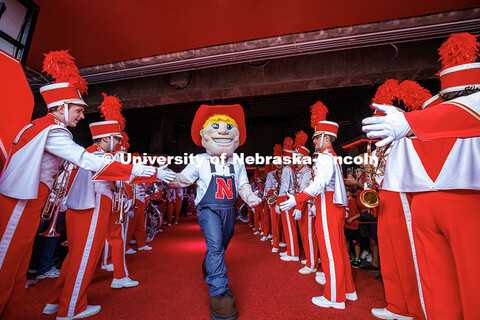 Herbie Husker gives out high-fives to the Cornhusker Marching Band before the start of the Nebraska 
