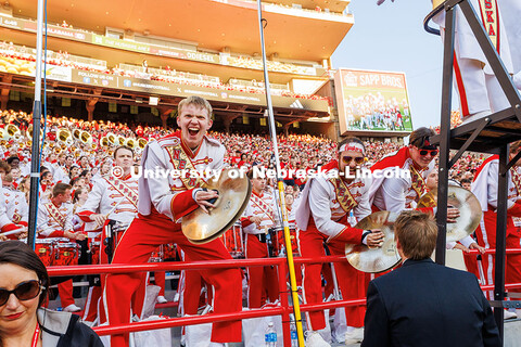 Davin Seeger, cymbalist for the Cornhusker Marching Band, crashes his cymbals and cheers during the 