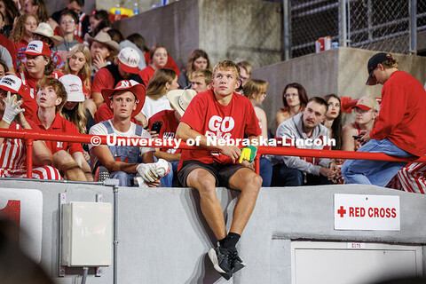 A student sits on the wall at the edge of the student section during half time at the Nebraska vs Ak
