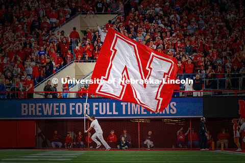 A spirit squad member runs with the oversized N flag in the end zone after a touchdown during the Ne