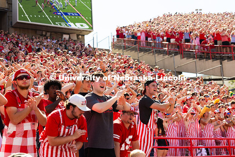 Students in striped overalls cheer from the southeast corner of Memorial Stadium during the football