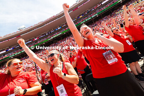 Flagbearer members in the alumni marching band scream "Go Big Red" after a touchdown. The alumni ban