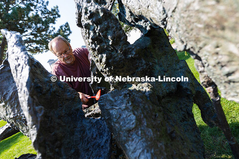 Les Bruning, owner of Bruning Sculpture in Omaha, uses a brush to remove dust and debris from Ruben 