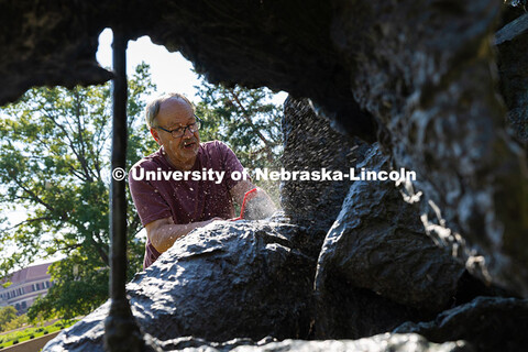 Les Bruning, owner of Bruning Sculpture in Omaha, uses a brush to remove dust and debris from Ruben 