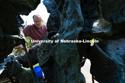 Les Bruning, owner of Bruning Sculpture in Omaha, uses a brush to remove dust and debris from Ruben 