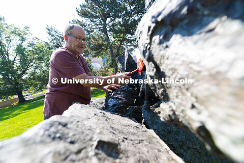 Les Bruning, owner of Bruning Sculpture in Omaha, uses a brush to remove dust and debris from Ruben 
