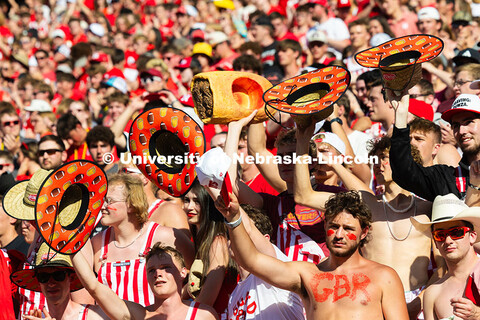 Fans in the student section inadvertently form a line with their Runza hats as they cheer at the sta