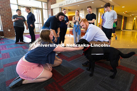 Students in the Honors Program smile as Jax, the program's therapy dog, gives a kiss to Emily Hughes