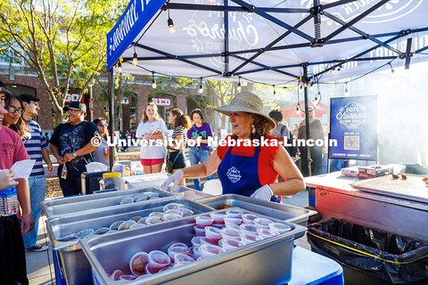 A worker from Papi Churros hands students free churros during Fiesta on the Green in front of the ci