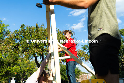 Alex Bjorman (center) looks toward Cole Bader, Theta Xi chapter president, as they clamp a board to 