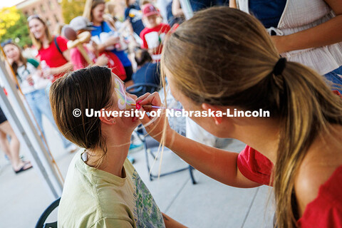 Stella Rostal has a butterfly painted on her face during the Cornstock Festival in front of Memorial
