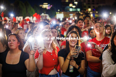 Spectators hold up their phone flashlights as they watch the Battle of the Bands. Homecoming parade 