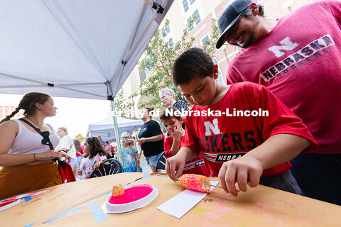 Zareh McKenzie, 6, peeks around his brother, Isaac, 10, making a bookmark with a corncob dipped in a