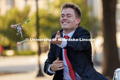 Homecoming royalty Caden Connelly tosses candy to spectators as he rides in a vintage car during the