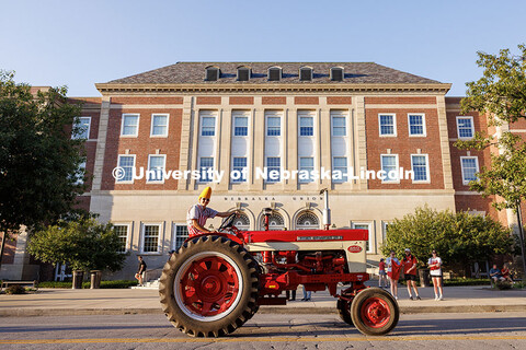 A member of the Tractor Restoration Club passes by the Nebraska Union during the homecoming parade. 