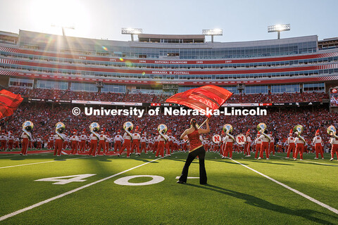 A member of the Cornhusker Marching Band Color Guard performs behind the rest of the band during the