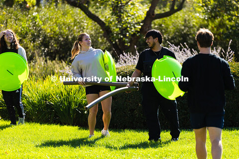 Students portraying "Spartans," with snow sled shields and pool noodle spears, laugh as they dodge p