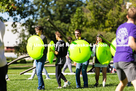 Students portraying "Spartans," with snow sled shields and pool noodle spears, huddle to block and d